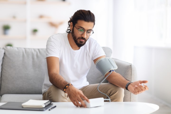 Young,Arab,Man,Sitting,On,Couch,,Checking,Blood,Pressure,And